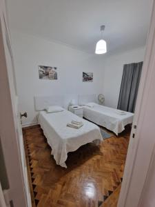 two beds in a white room with wooden floors at Boa Noite Casa de Hospedes in Lisbon