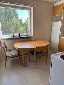 a kitchen with a wooden table and a window at Vehkaojan Kotoisa in Jämsä