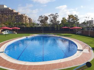 Una gran piscina en un parque con sombrillas rojas. en Holiday TorremarMED020, en El Borseral