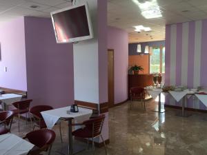 a dining room with tables and chairs and a tv on a wall at Hotel Marco Effe in Mestrino