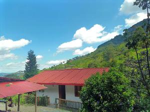 a house with a red roof next to a mountain at Posadas rurales arabi in Pereira