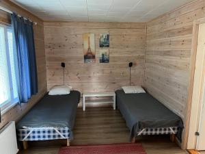 two beds in a room with wooden walls at SportHome in Rovaniemi