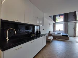 a kitchen with white cabinets and a sink and a living room at Apartament z Jacuzzi na wyłączność Dolina Baryczy in Żmigród