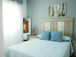 a bedroom with a bed with blue sheets and a mirror at O Cunchal Rooms in Dena
