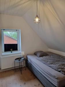 - une petite chambre avec un lit et une fenêtre dans l'établissement Willkommen in Frifelt Nähe Rømø mit wunderschönen Garten, à Skærbæk