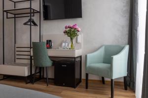 two chairs and a desk with a vase of flowers at Boutique-Hotel Weisses Haus Art in Bad Kissingen