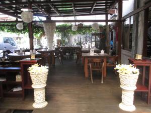 un restaurante con mesas de madera, sillas y flores en Ananda Resort Seminyak, en Seminyak