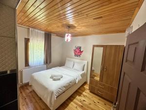 a bedroom with a white bed and a wooden ceiling at Haros Apart Hotel in Uzungöl