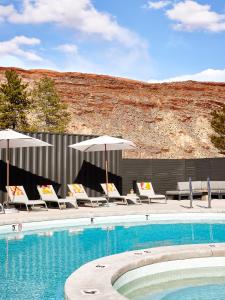 einen Pool mit Liegestühlen und Sonnenschirmen neben einem Pool in der Unterkunft Field Station Moab in Moab