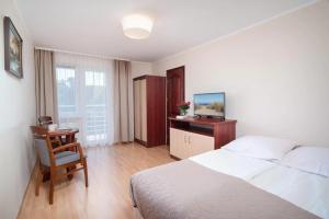Willa Cykas في ياستراوبيا جورا: غرفة نوم بها سرير ومكتب مع تلفزيون