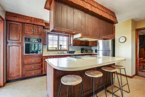 a kitchen with wooden cabinets and a island with bar stools at Wellsboro Farmhouse with Grill and Fire Pit! in Wellsboro