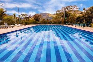 a large swimming pool with blue water at Granja Brasil puc 10 2 in Petrópolis