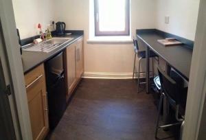 a kitchen with black counters and a sink and a window at Taff Trail Bunkhouse in Merthyr Tydfil