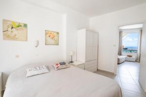 Dormitorio blanco con cama y vistas al océano en Mimis & Connie 1, en Karpathos