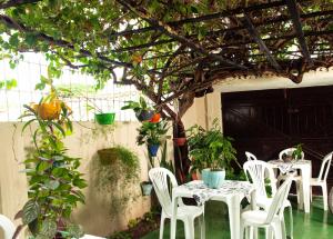 un patio con mesas blancas, sillas y plantas en Pousada Residencial Porto de Galinhas en Porto De Galinhas