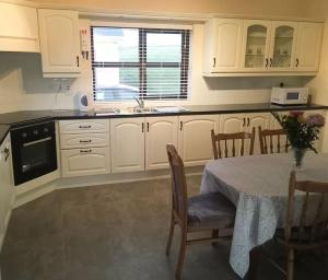 a kitchen with white cabinets and a table and a window at Entire home in Belmullet in Belmullet