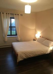 a bedroom with a white bed and a window at Entire home in Belmullet in Belmullet