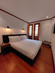 Cama blanca grande en habitación con suelo de madera en Concha y Toro 33 Hotel Boutique by Nobile, en Santiago