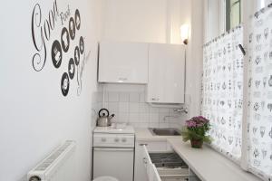 a white kitchen with white cabinets and a sink at Alice Apartment in Budapest