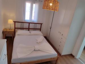 a bedroom with a bed with white sheets and a lamp at LIONS HOUSE PYTHAGORIO in Pythagoreio