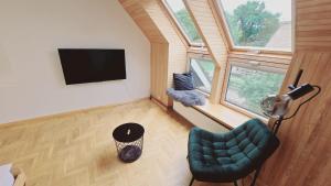a living room with a green chair and a flat screen tv at Nidos burė in Nida