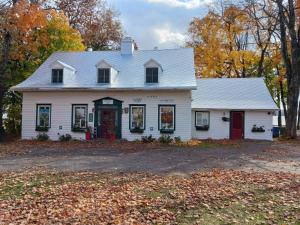 a white house with a red door at Auberge Les Blancs Moutons in Saint-Laurent-de-l'ile d'Orleans