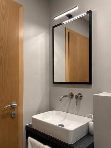 ein Badezimmer mit einem weißen Waschbecken und einem Spiegel in der Unterkunft Apartments Rombon in Bovec