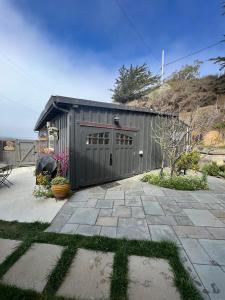 Carriage House Waterfront On Tomales Bay With Dock في Marshall: مبنى رمادي مع مرآب مع فناء
