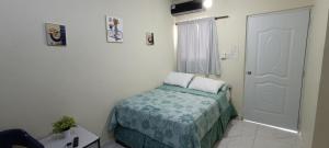 a small bedroom with a bed and a door at Alojamiento Acogedor in San Felipe de Puerto Plata