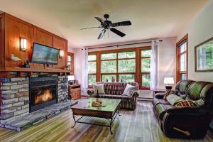 a living room with a fireplace and a ceiling fan at Tremblant Les Eaux D - Mont-Tremblant in Mont-Tremblant