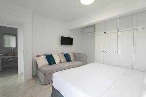 a white bedroom with a bed and a couch at Villa Sunrise Psarou in Psarou