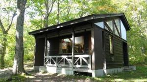 eine schwarze Hütte im Wald mit einem Baum in der Unterkunft Towada City Utarube Campsite - Vacation STAY 00407v in Utarube