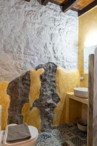 a bathroom with a stone wall with a sink and a toilet at Villa Margarita Studio in Patmos