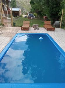 une grande piscine bleue avec deux chaises et un chien dans l'établissement Cabañas Nuestras Raices Potrerillos, à Potrerillos