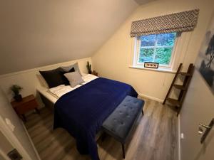 a bedroom with a bed with a blue blanket and a window at Leilighet ved sjøen i idylliske Risør in Risør