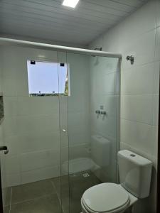 a bathroom with a toilet and a glass shower at Pousada Villa Encantada Ilha do Mel in Ilha do Mel