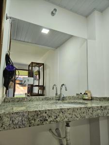 eine Badezimmertheke mit einem Waschbecken und einem Spiegel in der Unterkunft Pousada Villa Encantada Ilha do Mel in Ilha do Mel