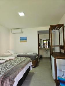 ein Hotelzimmer mit 2 Betten und einem Spiegel in der Unterkunft Pousada Villa Encantada Ilha do Mel in Ilha do Mel