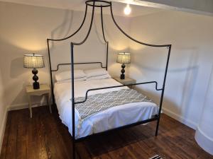 カーリングフォードにあるDarcy Magee Apartment No1のベッドルーム1室(黒い天蓋付きベッド1台、ランプ2つ付) +2枚の写真