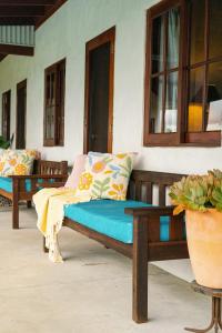 a wooden bench sitting on a porch with pillows at Blue Fattoria Luxury Farm Accomodation in Fernside