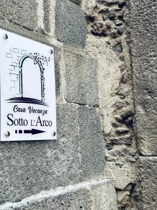 a sign on the side of a stone wall at Sotto l'Arco in Acireale