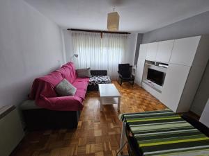 a living room with a pink couch and a table at EnVIVEIRO Destino Playa de Covas in Viveiro