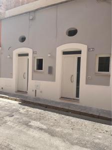a row of three doors on a white building at Dimora Apulia 5 in Gallipoli
