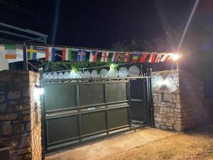 a green gate with flags on top of it at night at Camping Albania-Secret Village Den in Sarandë