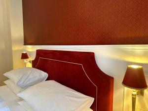 a bed with white pillows and a red headboard at Aviano Boutiquehotel in Vienna