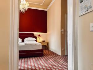1 dormitorio con cama y pared roja en Aviano Boutiquehotel, en Viena