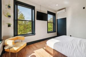 a bedroom with a bed and a chair and windows at Society Hill Hotel in Philadelphia