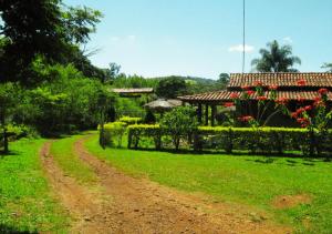 un camino de tierra que conduce a una casa con jardín en Pousada Rural Vargem do Cedro, en Belo Vale