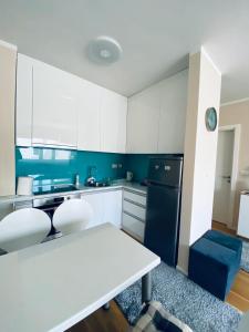 a kitchen with white cabinets and a white table at Apartman Otoka-Meandar in Sarajevo +12 photos