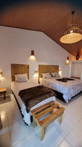 a bedroom with two beds and a table at Vila Capininga Ecopousada in Santo Amaro